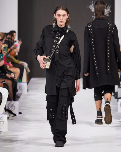 A male model wearing an all black look designed walking down the runway