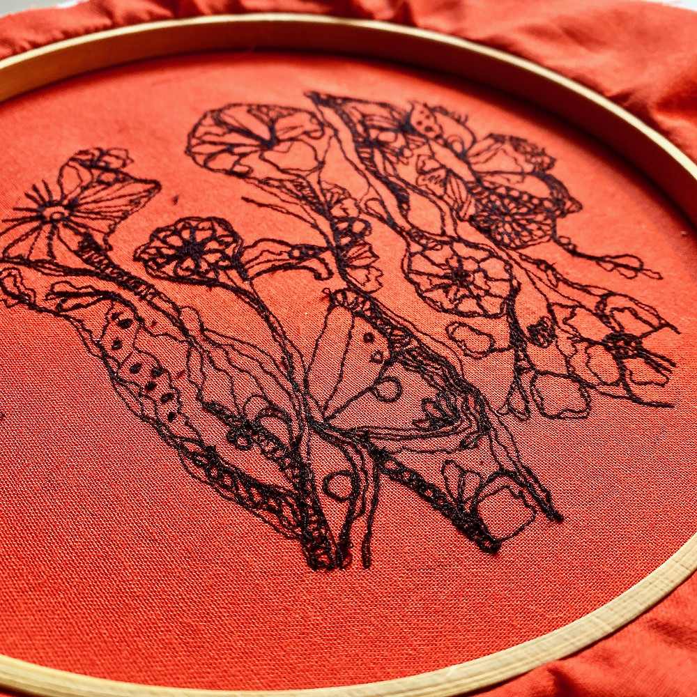 Freehand machine embroidered floral design with black cotton on orange fabric