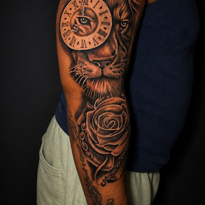 Detailed Lion of Time tattoo with rose on a man's arm