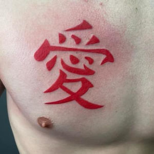Red Kanji symbol for love tattooed on a person's chest.