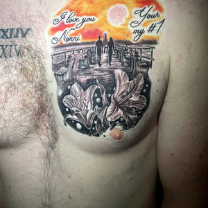 Chest tattoo of a sunset memorial with lilies and text.