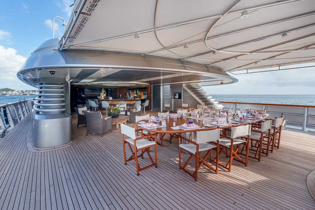 Alfresco dining setup on the deck of a sailing superyacht overlooking the ocean.