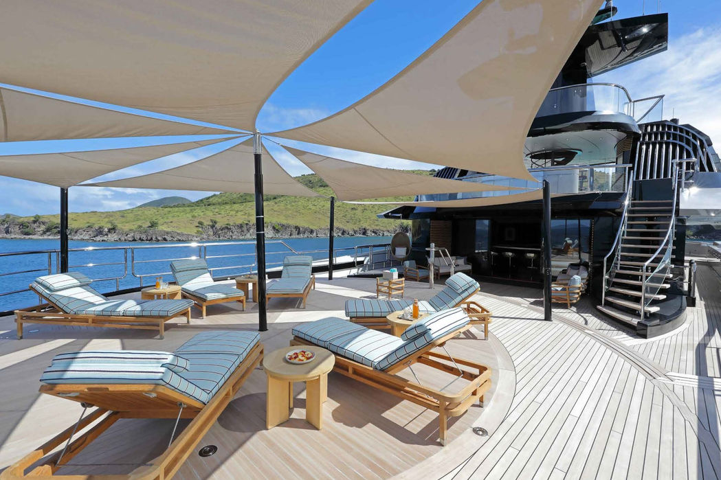 Large pool deck with loungers and ocean-view seating on Whisper superyacht.