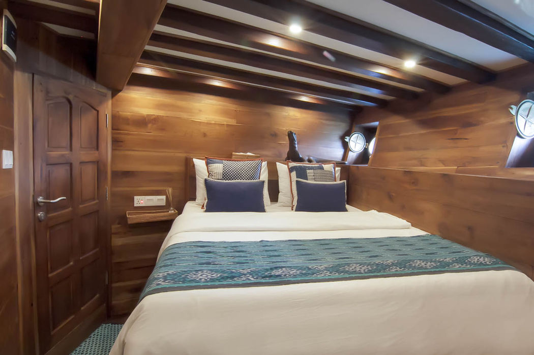 Guest cabin with double bed onboard Tiger Blue Phinisi luxury yacht in Komodo with Navélia Yacht Charters Indonesia.