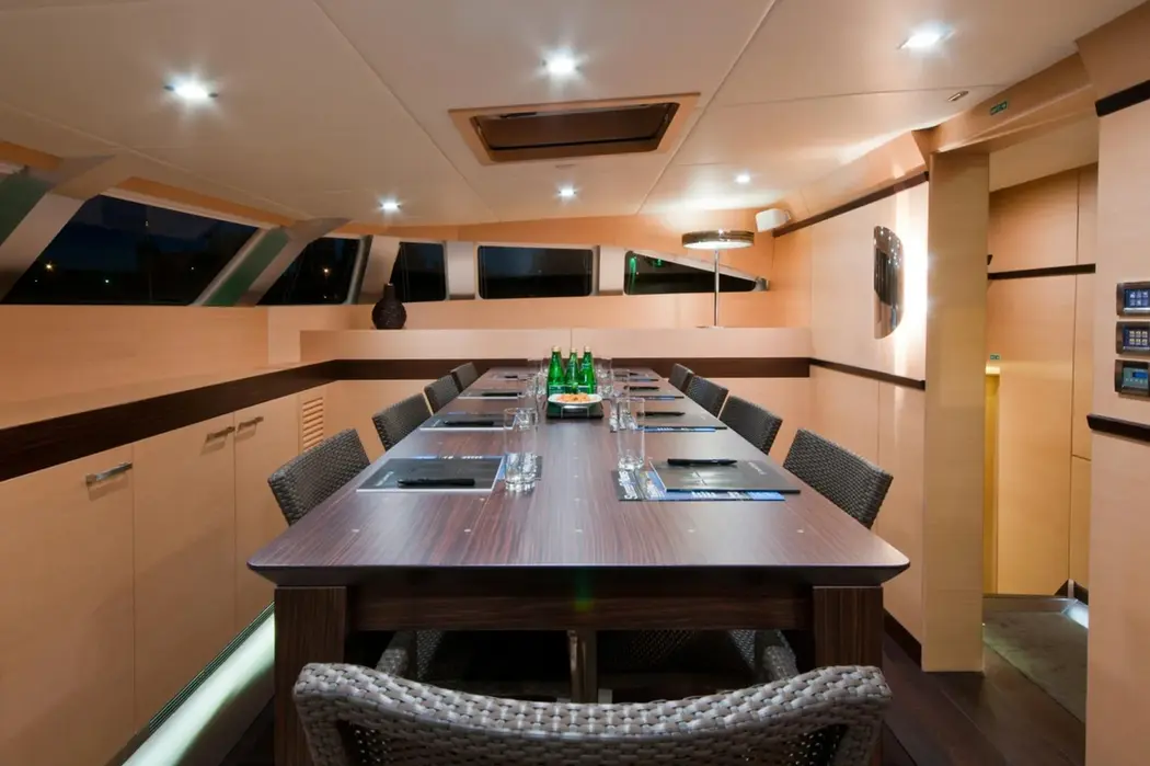 Indoor dining table on Ipharra catamaran prepared for charter meals