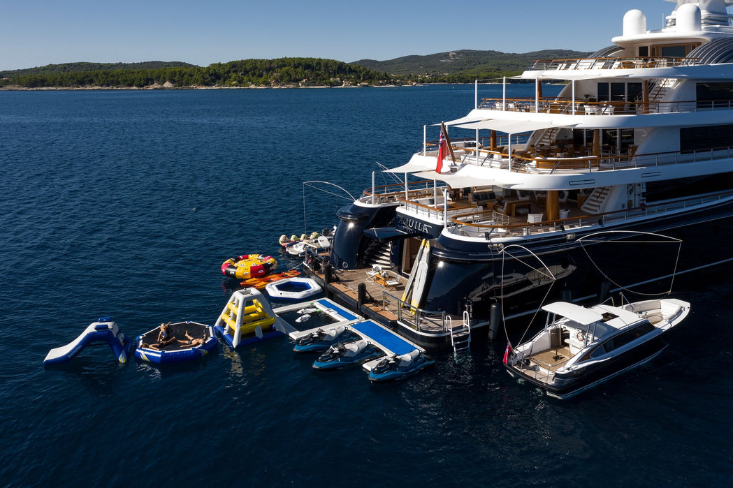 aerial view of Aquila superyacht anchored with jet skis and inflatable water toys in the Mediterranean
