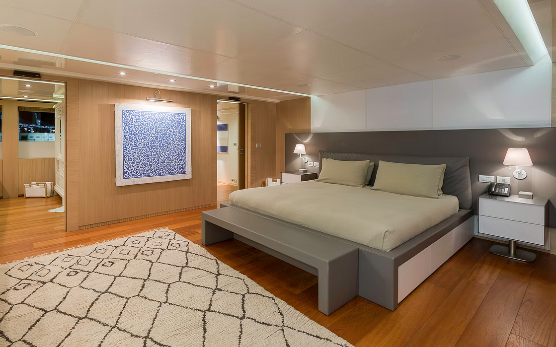 Elegant guest suite aboard Vicky featuring a king bed, seating area, and warm lighting—ideal for multi-day luxury charters.