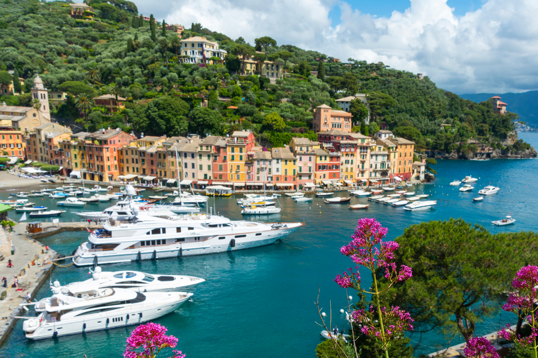 Portofino harbor with luxury yachts moored in turquoise water and colorful waterfront buildings along the Ligurian coast