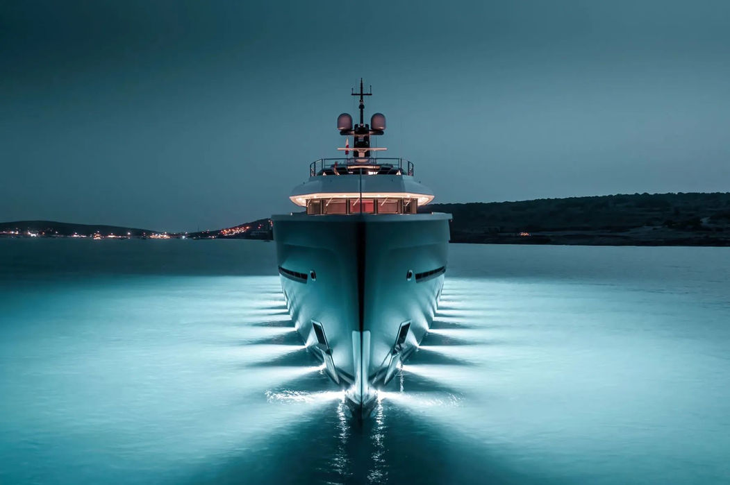 Forward night view of Come Together yacht cruising with illuminated hull lights.