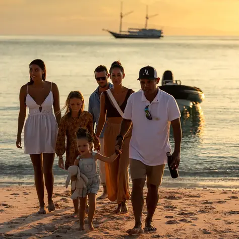 Family walking on a beach at sunset during a luxury Indonesian yacht charter, with the yacht and tender anchored offshore.