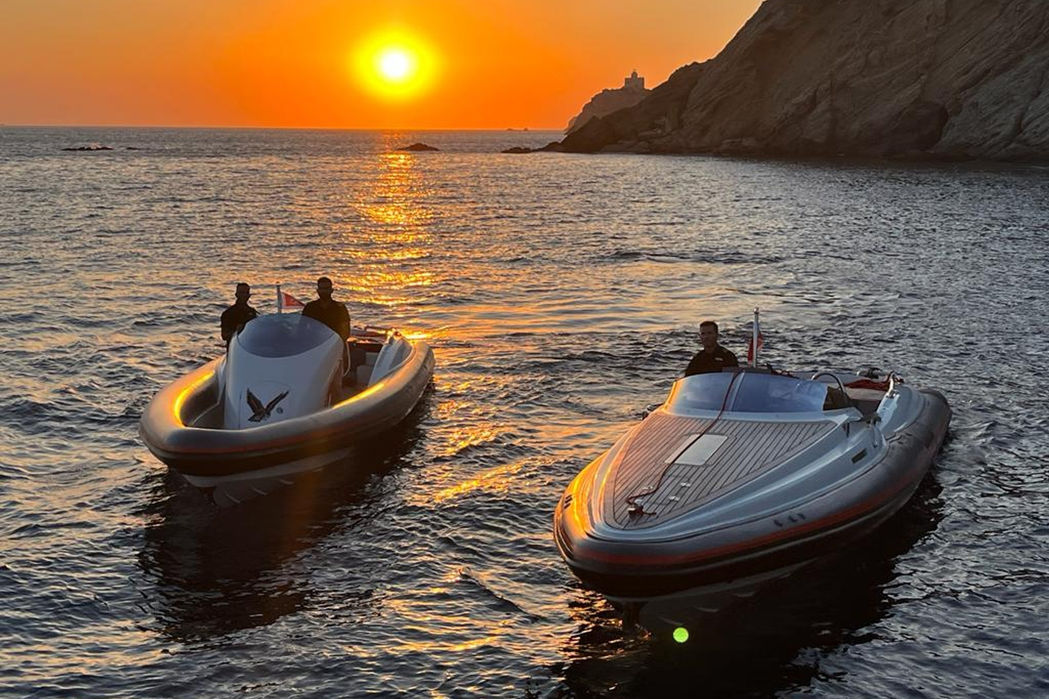 Tenders and chase boats positioned behind a sailing superyacht at anchor.