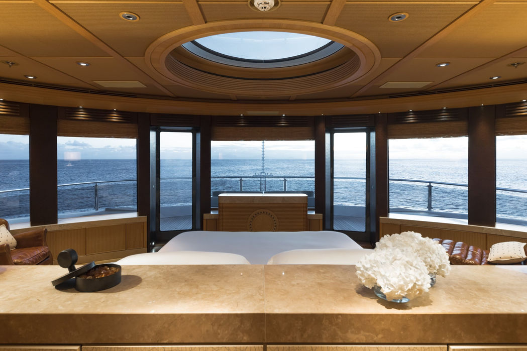 Guest bedroom suite on Naia superyacht with large bed and panoramic windows.