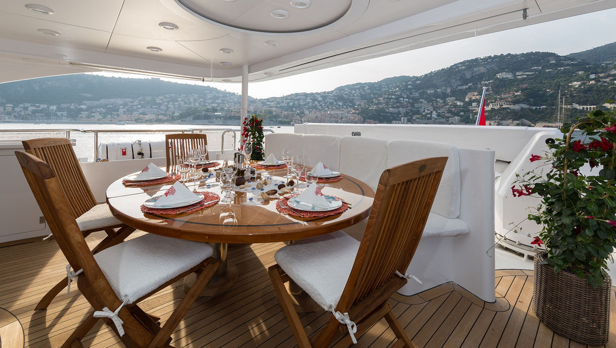 Aft deck dining setup aboard M/Y Bina with sea views across the Riviera coastline