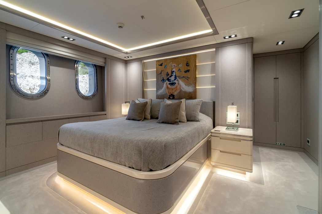 VIP cabin on O’Mathilde with a central bed, soft backlighting, and porthole views.
