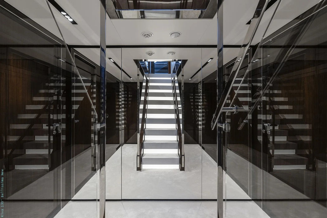 Stylish glass-framed staircase inside the Riva 130 Dolcevita leading to lower and upper decks.