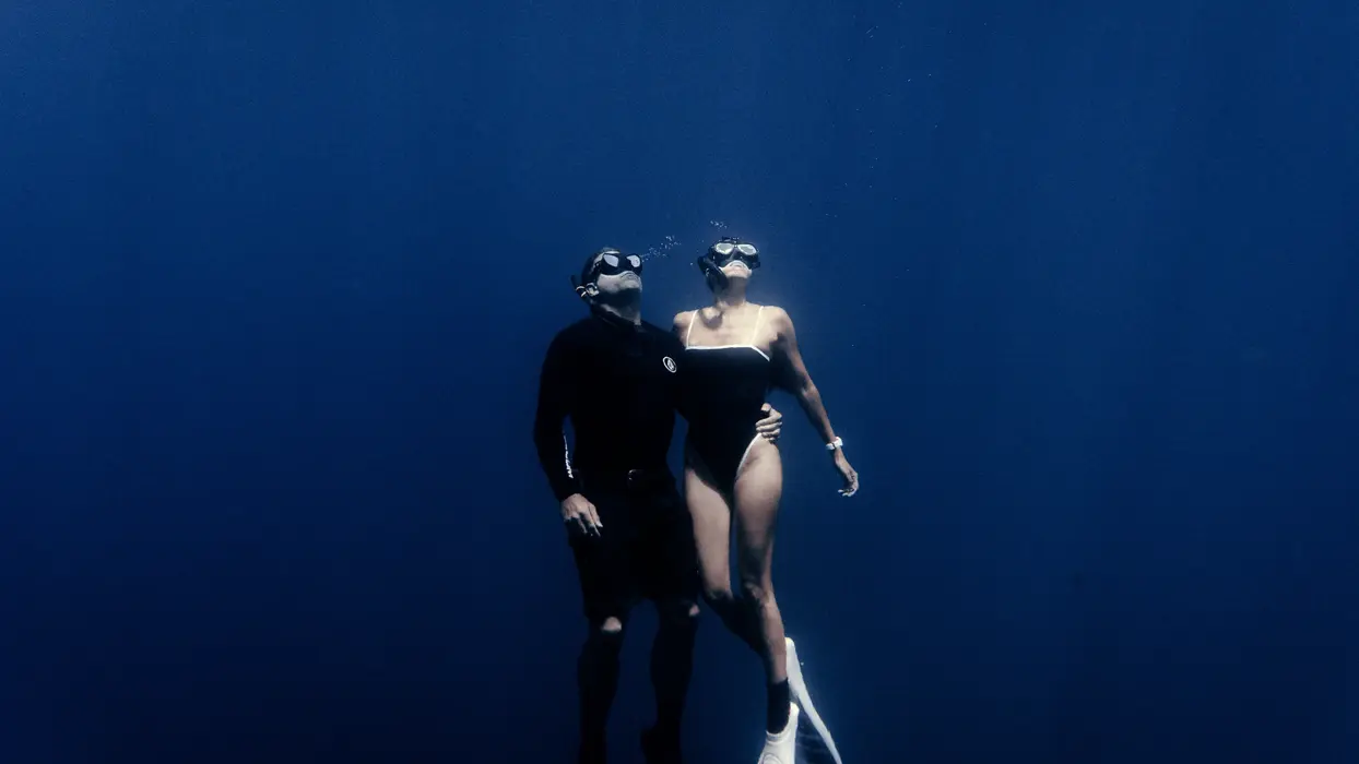 Couple freediving together in the deep blue Banda Sea as part of an exclusive private yacht charter in Indonesia.