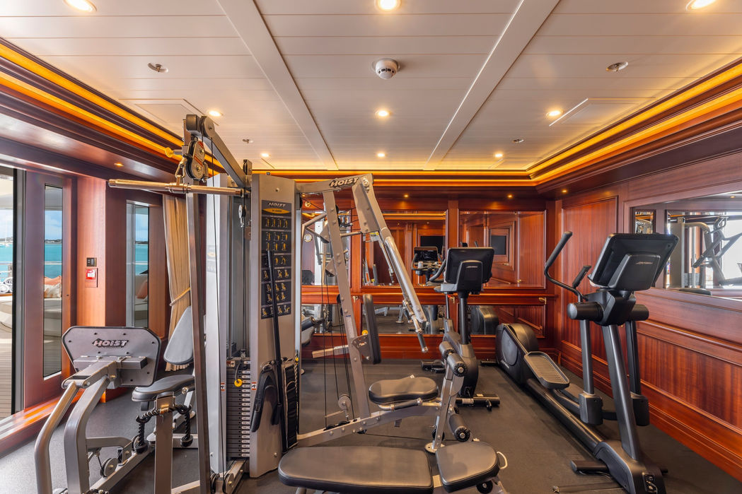 Fully equipped gym aboard Gigia featuring cardio machines and weights facing the ocean.