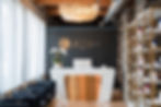 Elegant salon reception desk at Jessi Beauty Space with ambient lighting, crystal chandelier, blue armchairs, and orchid arra