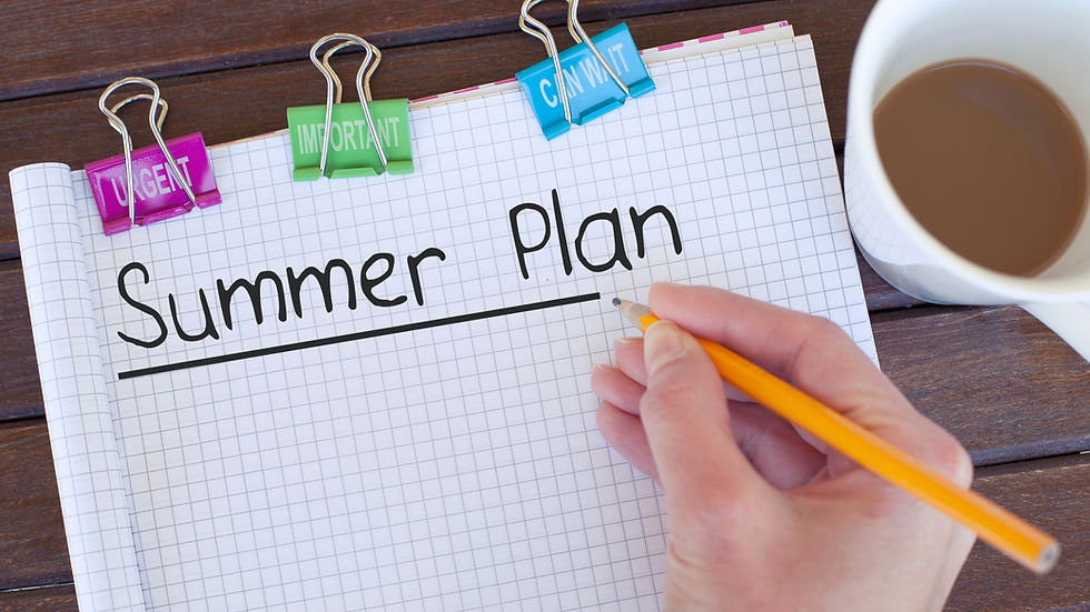A note pad that says, "Summer Plan" on top of a brown table with someone's hand holding a pencil and a coffee cup next to the note pad.