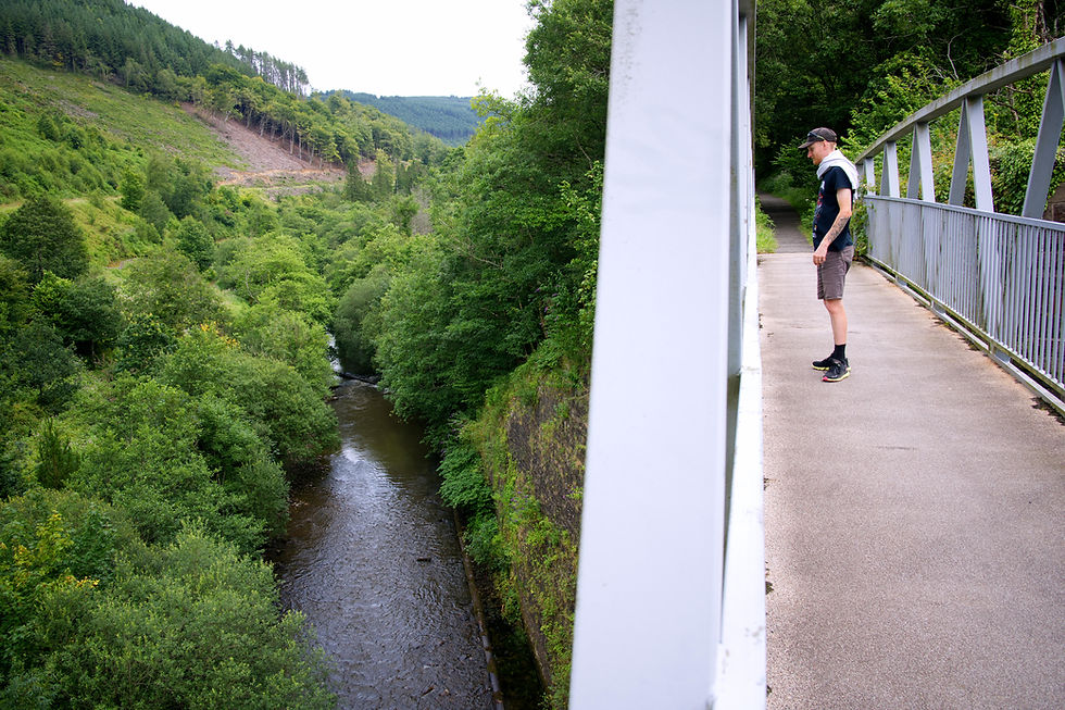 Man standing on bridge looking over a river valley in the Afan Forest, Wales.