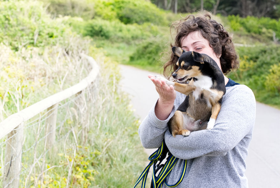 Pet portrait of owner and dog. A chihuahua is held by owner.