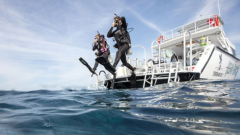 two divers doing a giant stride entry off the back of a dive boat into the ocean
