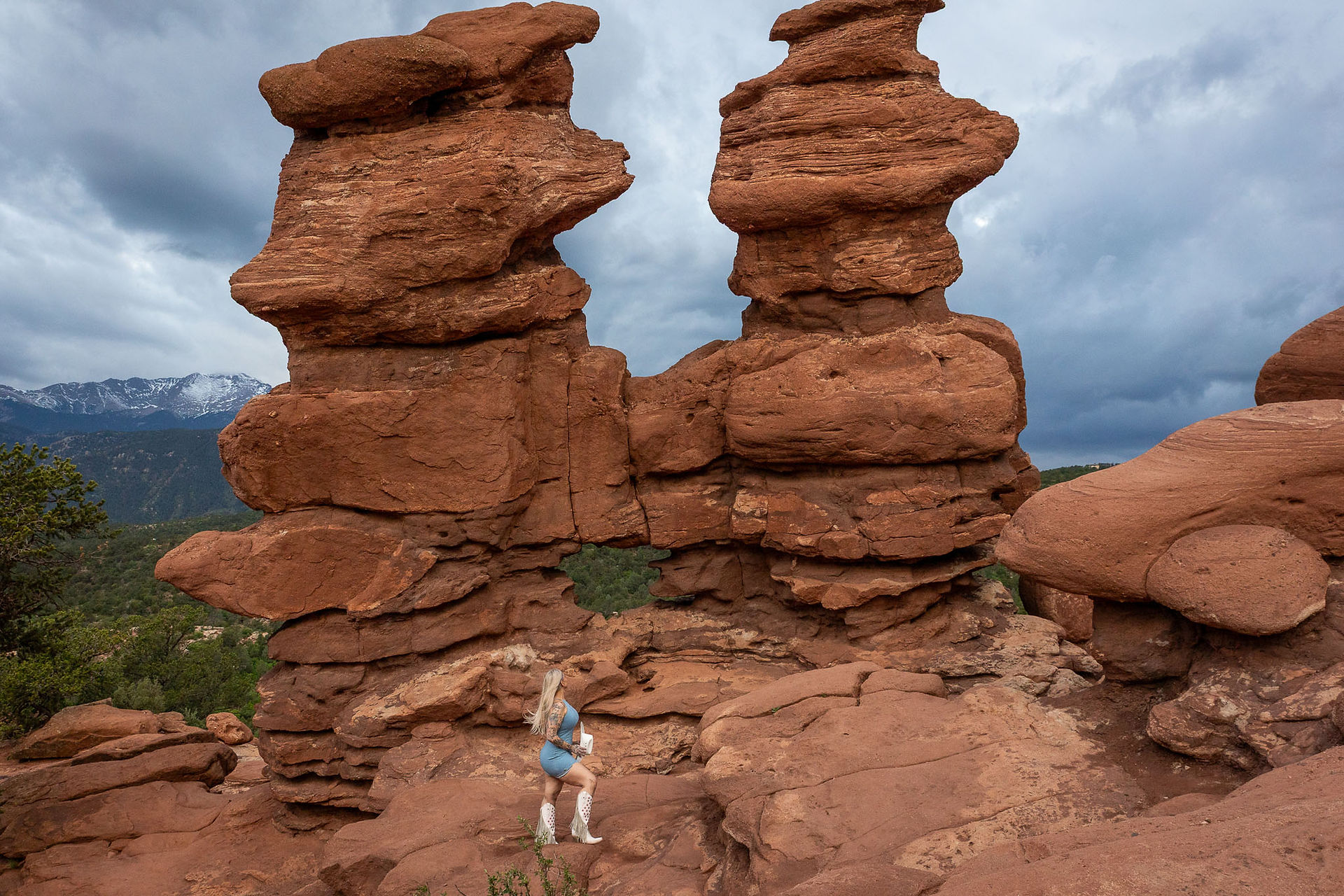 Lifestyle portrait of woman in denim dress, white cowboy hat, and star-patterned boots at Garden of the Gods near Siamese Twins