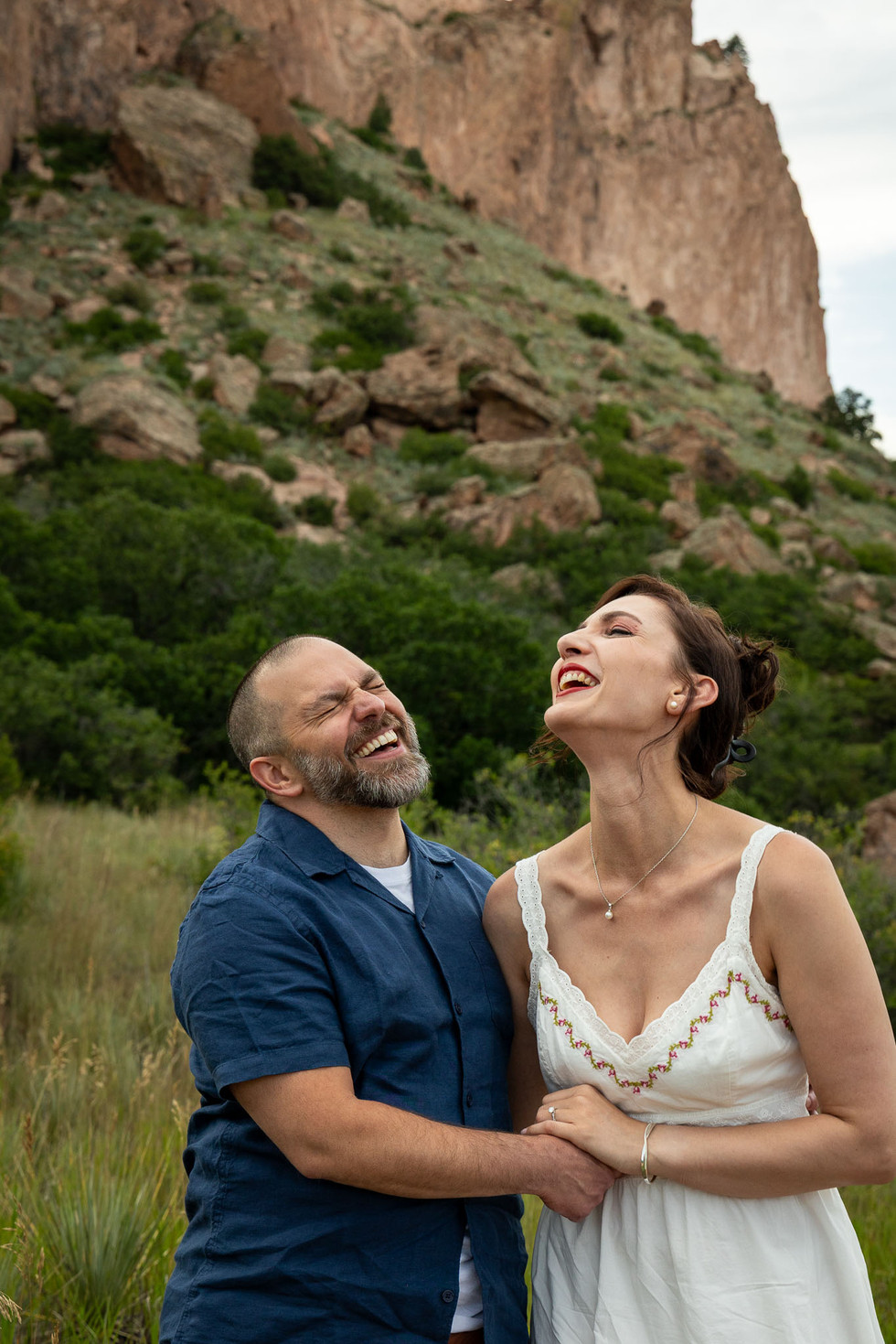 Romantic moment of Lucie and Erick surrounded by wild grasses and red rock spires, captured at sunset in Garden of the Gods.