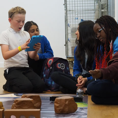 group of primary school pupils coding a sphero robot to navigate a course in the robot rescue workshop