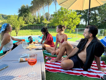 Nesting Away coliving guests enjoying Aperol Spritz and conversation by the pool in the Italian countryside near Rome