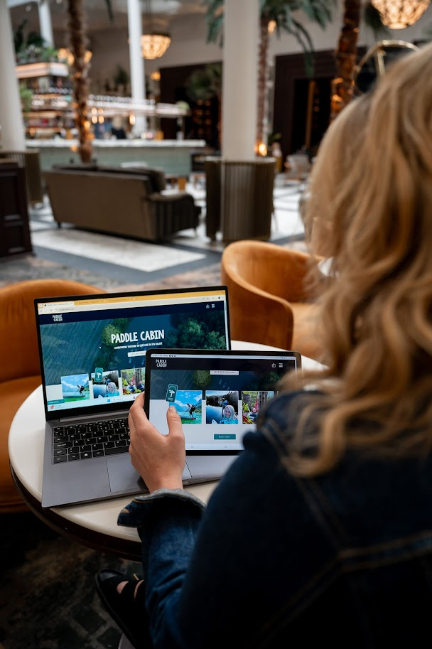 RDD brand photograph of Rachael looking at the paddle cabin website on multiple devices