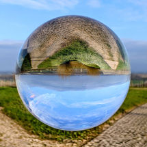 Lensball mit Gabelung gepflasterter Feldwege in Weinbergen, grüne Wiese mit Busch in der Mitte, unter blauem Himmel.