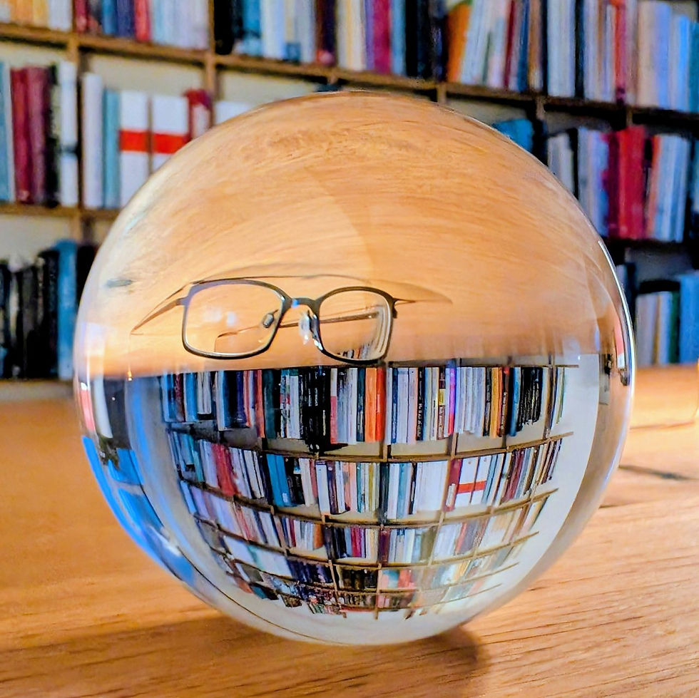 Lensball mit Spiegelung einer Brille vor einem Bücherregal – Symbolbild für Erkenntnis, die über bloßes Wissen hinausgeht