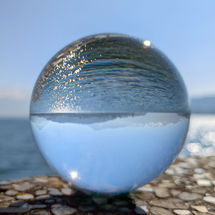 Lensball mit Spiegelung von Bergen, See und blauem Himmel in Luzern – Symbolbild für den Blick auf das große Ganze