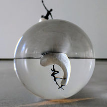 Lensball mit Spiegelung einer Skulptur, die Hilfe unter Menschen darstellt – Symbolbild für Beziehung und Verbundenheit