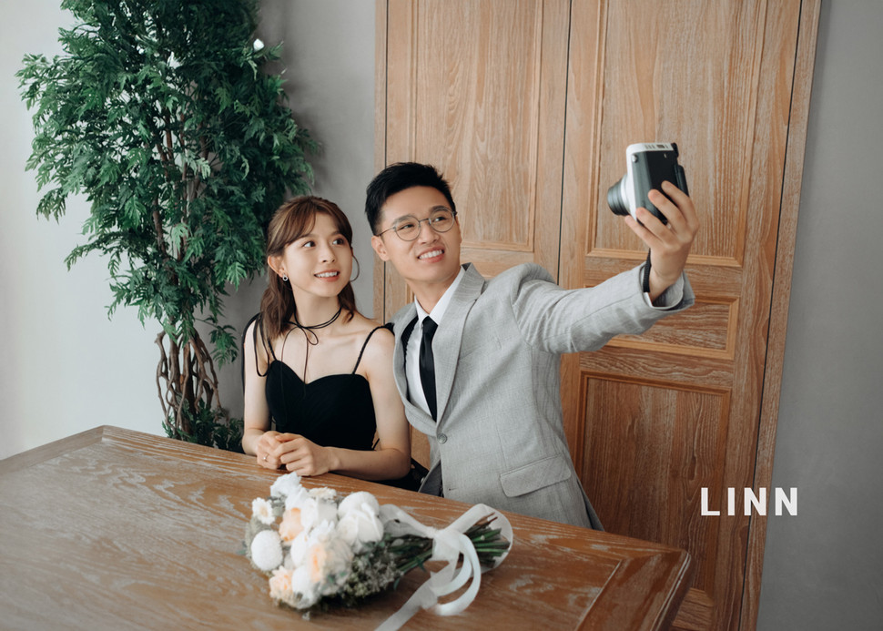 

Couple in black dress and suit taking selfie with instax camera.