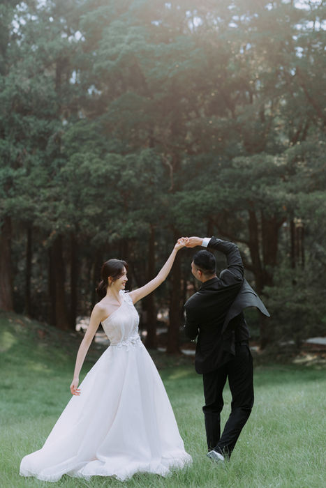 森林草地婚紗，新郎牽手引導新娘旋轉跳舞。 / Couple dancing in Huisun Forest, groom spinning the bride on grass.