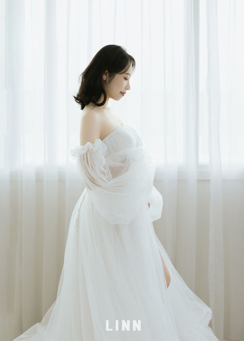 身穿白色婚紗的孕婦在窗邊拍第二胎孕照