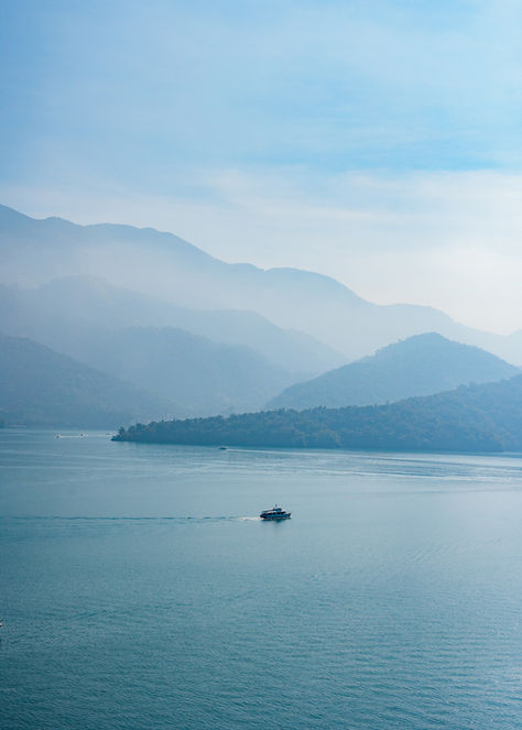 日月潭涵碧樓晨曦中的湖光山色,遠眺山巒重疊與湖上小船