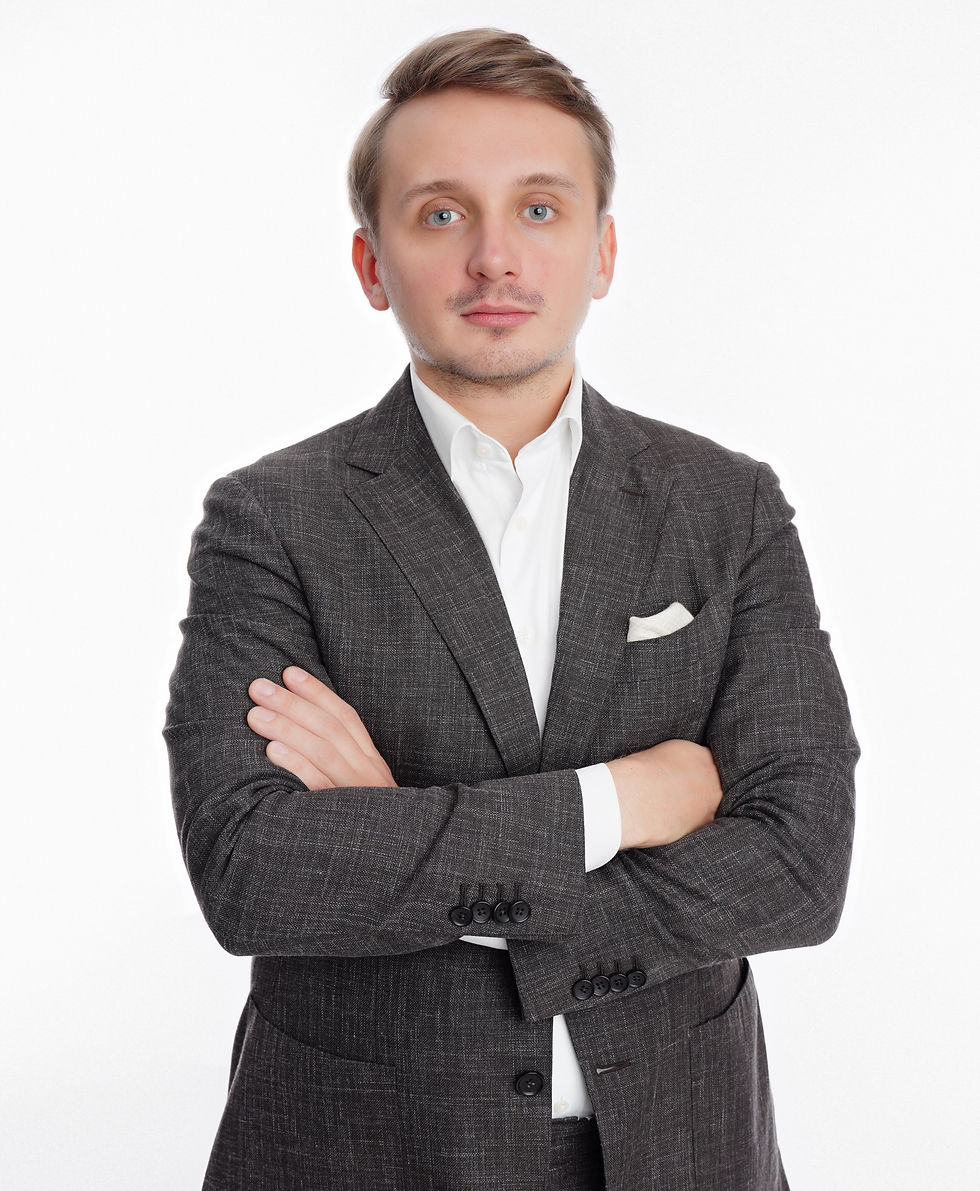 Person in a gray suit with arms crossed, standing against a plain white background. The mood is serious and professional.