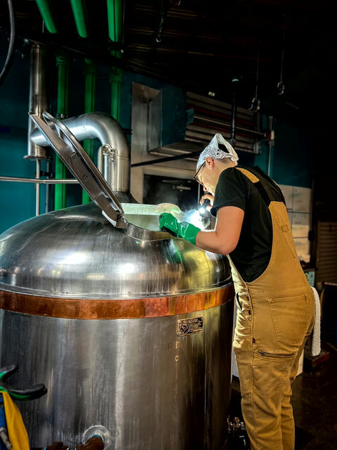Abbie looking inside the brew kettle in a brewery
