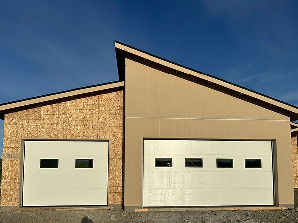 Double beige garage doors with windows installed on a brick house
