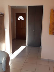 Entrée d’origine avant rénovation avec porte en bois, placard intégré et carrelage clair.
