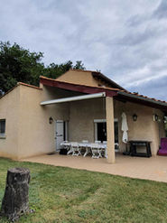 Vue latérale de la maison à Pont-de-l’Isère avant rénovation, montrant la terrasse couverte et l’avancée de toit existante