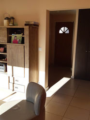 Vue de l’ancien salon avant travaux avec mobilier en bois et accès direct à l’entrée.