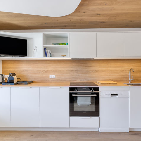 Cuisine moderne avec façades blanches, grand plan de travail en bois et rangements intégrés à Courchevel.