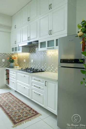 Kitchen interior design with stainless steel extractor hood and gas-on-glass hob. Backsplash features square mosaic tiles with metallic accents.