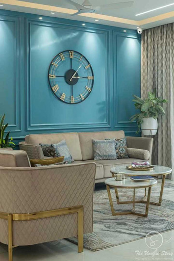 Teal paneled wall with a central clock and beige sofa with gold accents.