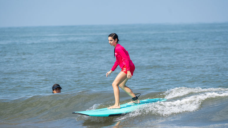 Beginner kid surfing her first wave with coach Rudy in Puerto Vallarta, Mexico.