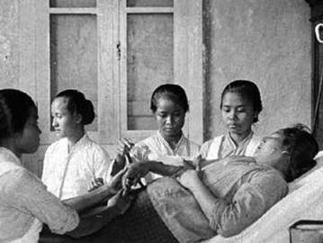 Bidan dan siswa kebidanan sedang menangani pasien pribumi, Semarang 1910. Sumber: Liesbeth Heeselink, The Early Years of Nursing.